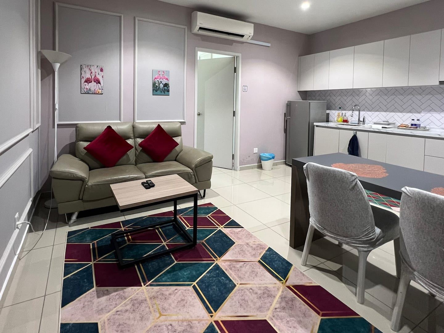 The living area of the Hyde Tower apartment at i-City, with a sofa, patterned rug and dining table.